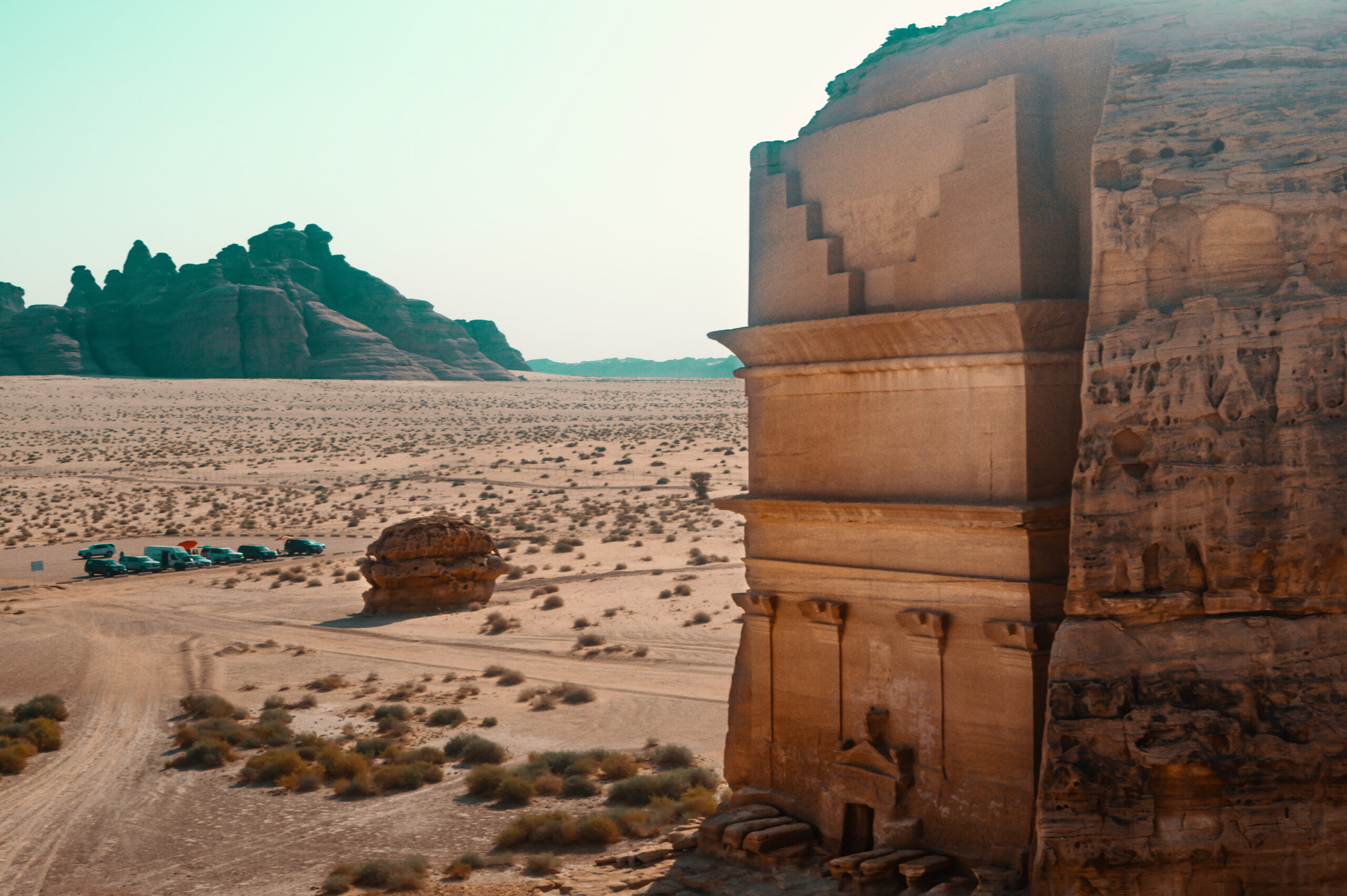 An aerial view of a carved tomb facade in Hegra, a UNESCO World